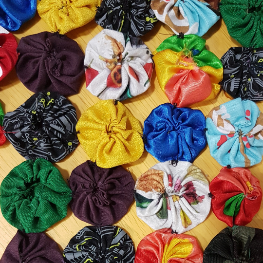 Imagem de pequenas fuxicos, flores artesanais feitas de retalho.